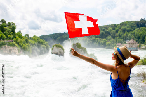 Young female tourist with swiss flag near the famous Rhine waterfall in Switzerland photo