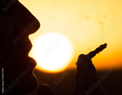 Silhouette of male smokers in the sunset