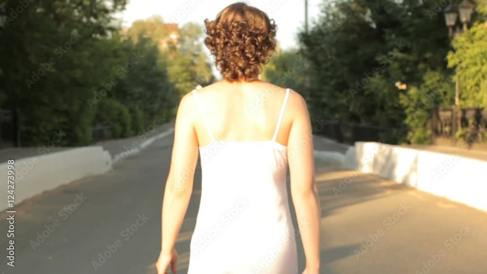 Young woman in a nightie goes on the road, rear view Young woman in a nightie goes on the road, rear view