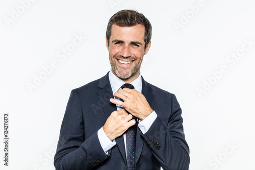 Fotografie happy bearded businessman fixing his dandy tie with elegant knot