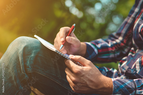 Man writing in his notebook in forest