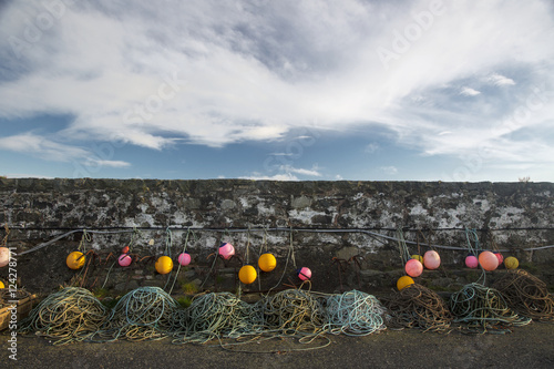 Colourful buoys and ropes hanging along a stone wall;Dumfries and galloway scotland photo