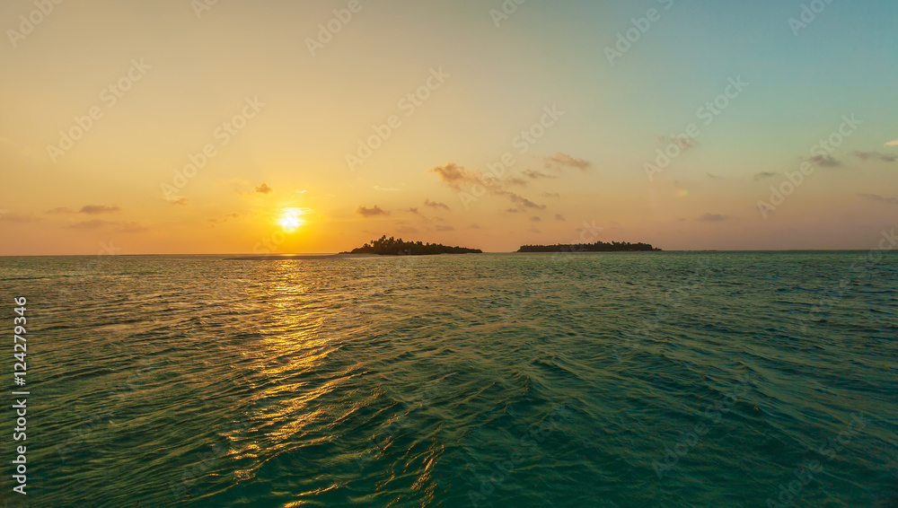 Romantic orange sunset with tropical island, Maldives Romantic orange sunset with tropical island, Maldives