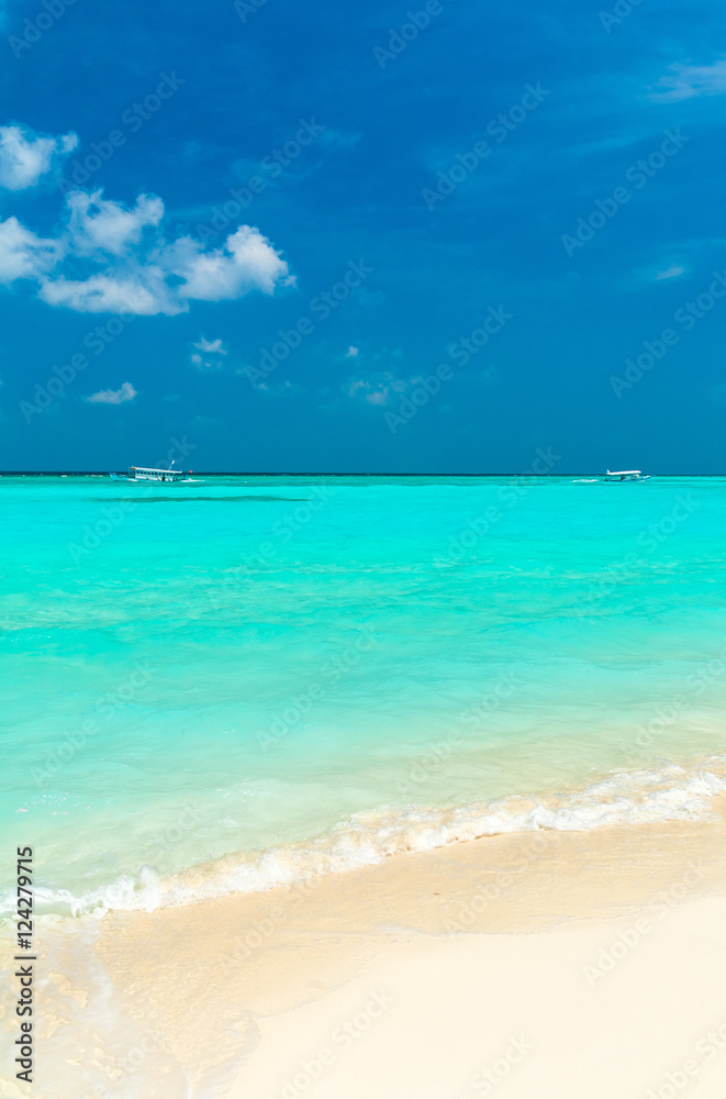 Seascape with rolling waves on a sandy beach and boats, Maldives