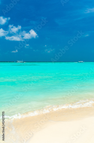 Seascape with rolling waves on a sandy beach and boats, Maldives