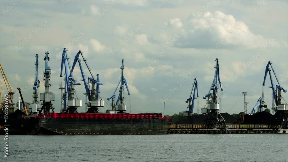 In the Port many cranes working on coal heaps, ship and clouds background In the Port many cranes working on coal heaps, ship and clouds background