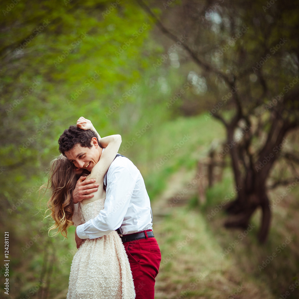 Lovely brunette man in red trousers hugs his woman tender while Lovely brunette man in red trousers hugs his woman tender while