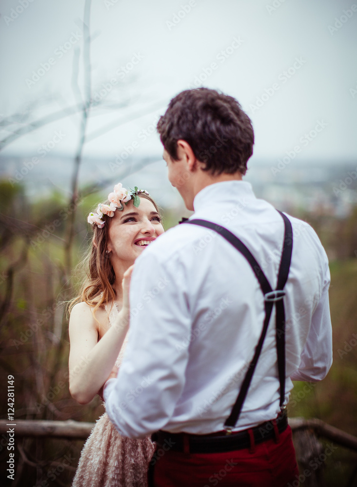 Radiant woman in flower wreath looks at her man in braces Radiant woman in flower wreath looks at her man in braces