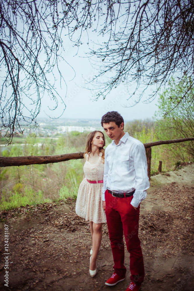 Lady in pink dress walks to her man in red trousers