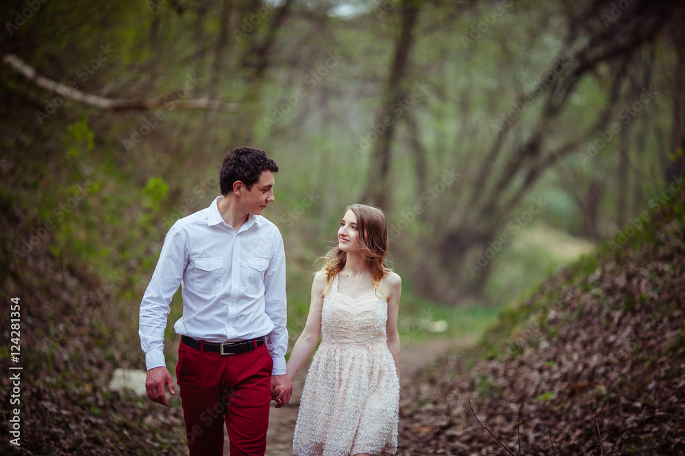 Tall man admires his lady in peach dress while walking in the pa Tall man admires his lady in peach dress while walking in the pa