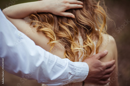 Fotografie Man's broad palm touches woman's back covered with blonde curls