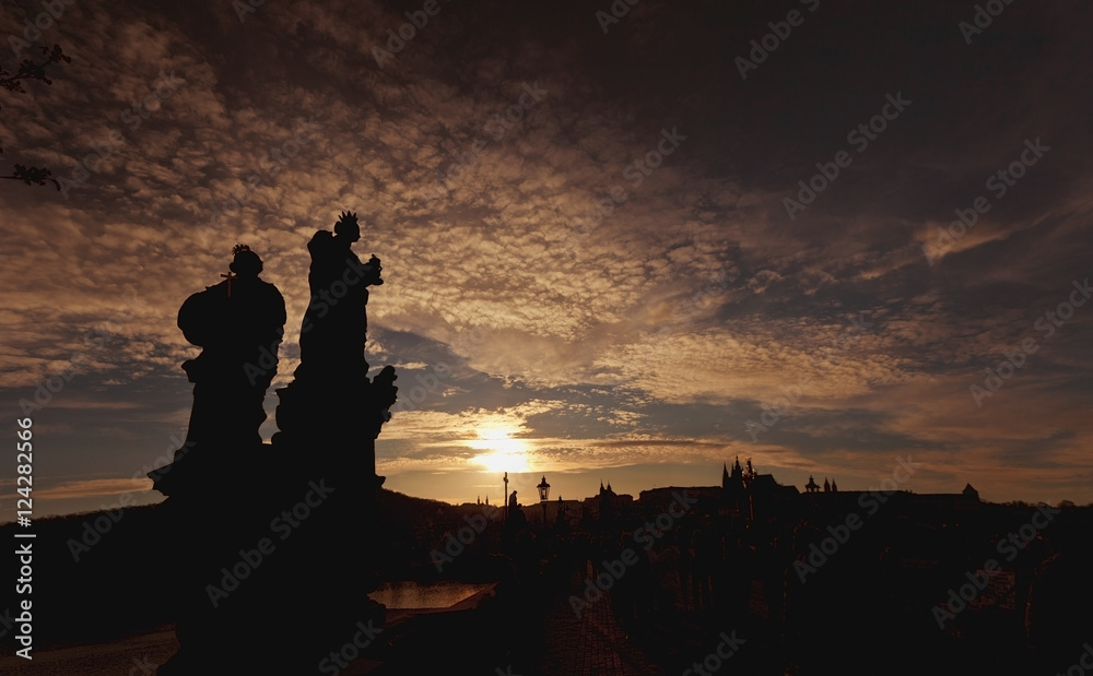 Silhouette of two statues and the skyline in the distance at sunset;Prague, czech republic Silhouette of two statues and the skyline in the distance at sunset;Prague, czech republic