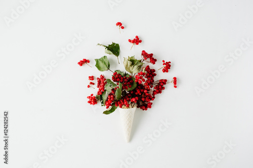 ice cream waffle cone with red rowan bouquet on white background, flat lay, top view. autumn wallpaper