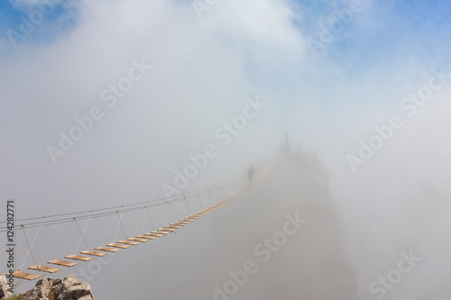Canvastavla Man crossing the chasm on the hanging bridge in fog (focus on the middle of brid