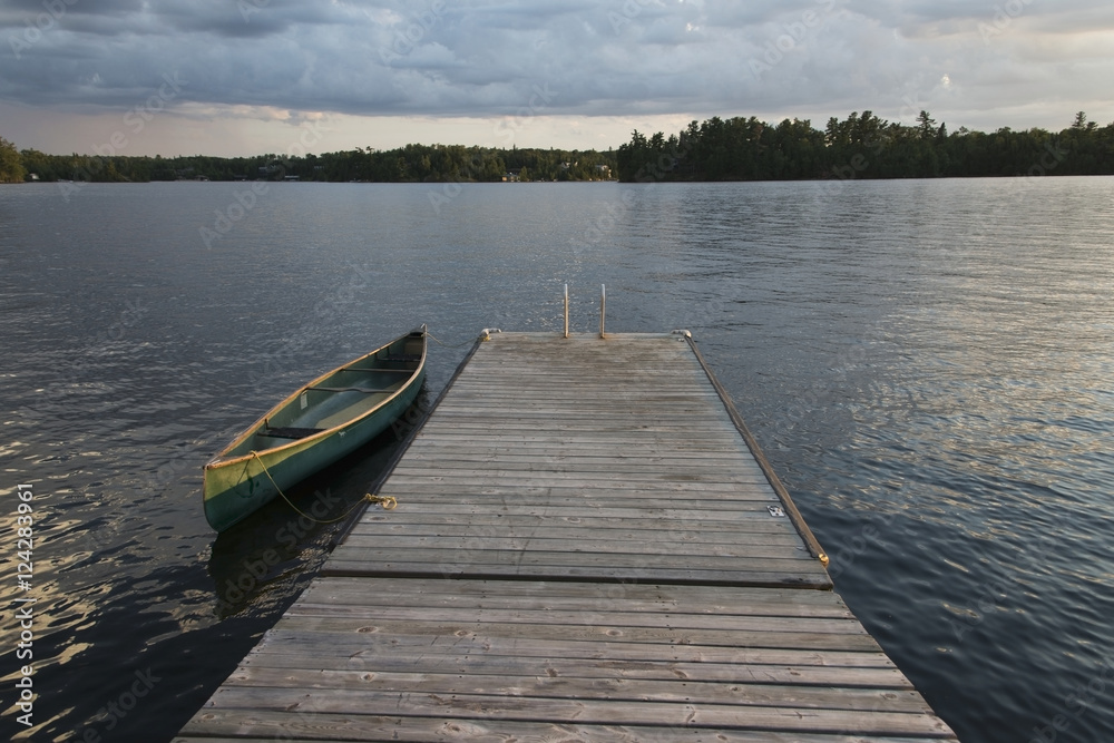 A canoe tied to a wooden dock on lake of the woods at sunset;Keewatin ontario canada A canoe tied to a wooden dock on lake of the woods at sunset;Keewatin ontario canada