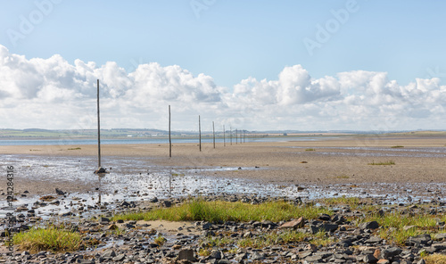 Waymarking poles stretching across the causeway at Holy Island in Northumberland showing a safe route for walkers.