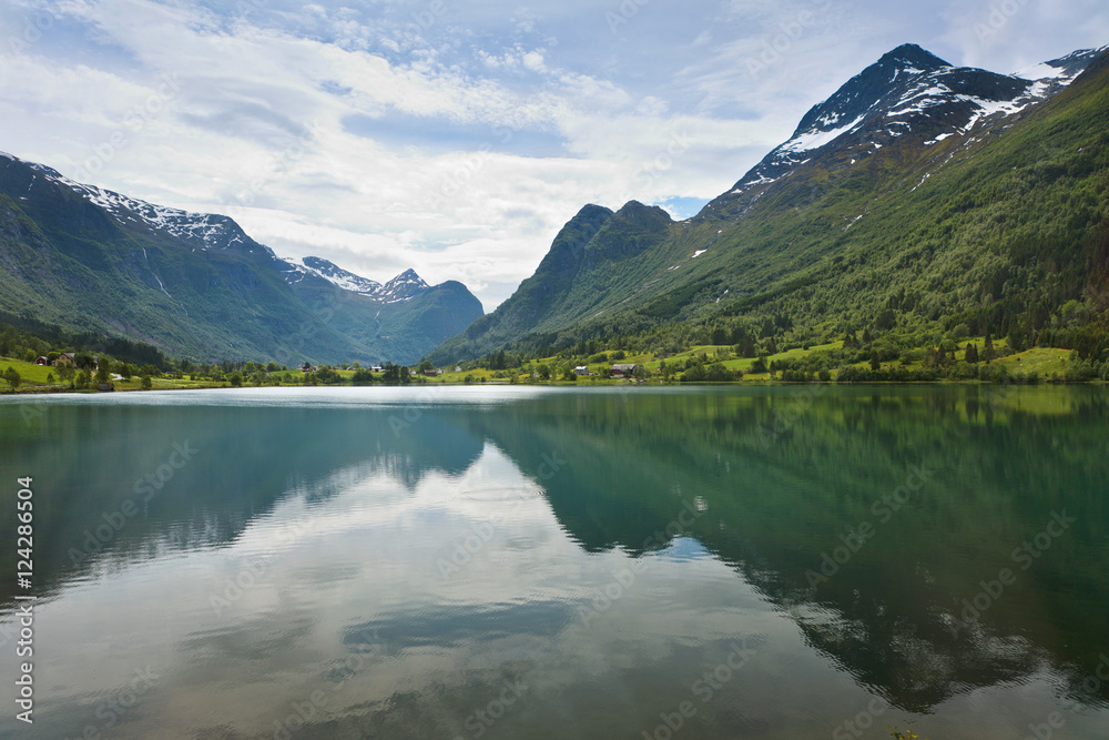 Mountains and sky reflected in the tranquil water surrounded by mountains; Olden, Norway Mountains and sky reflected in the tranquil water surrounded by mountains; Olden, Norway