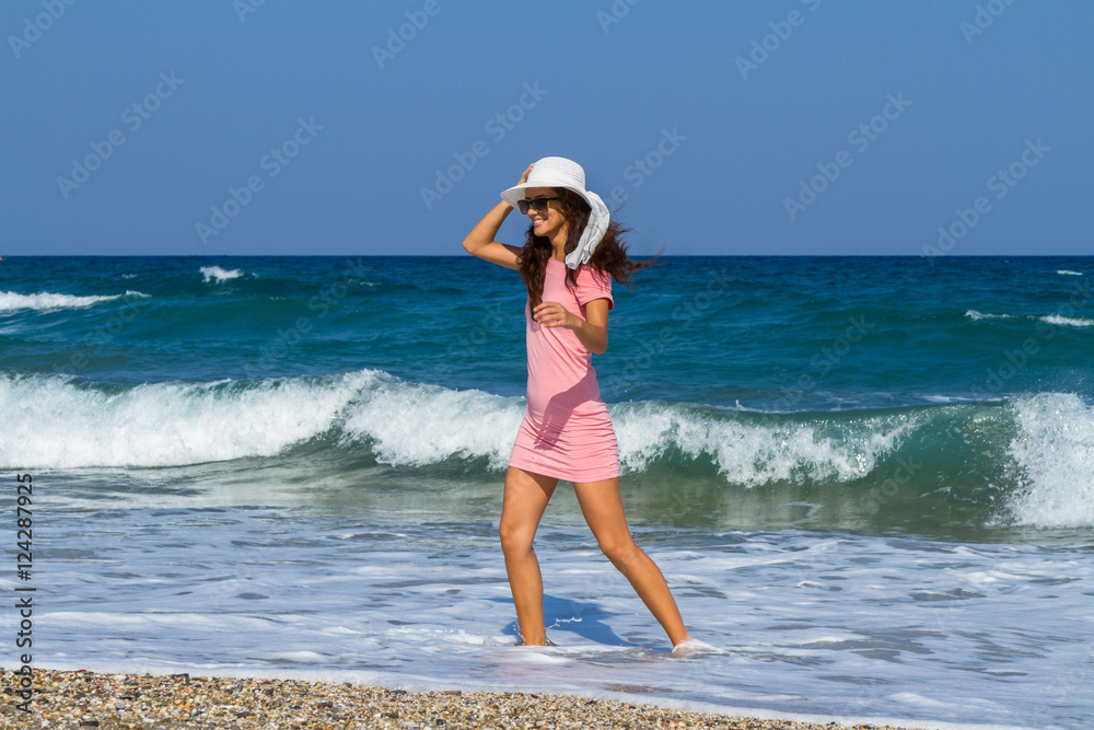 Beautiful carefree woman in short pink dress at the beach.