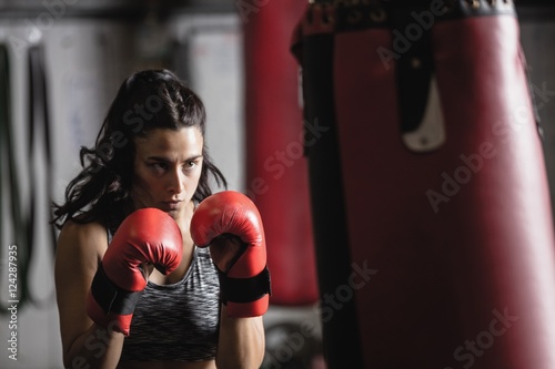 Female boxer practicing boxing with punching bag photo