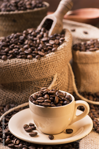 chicchi di caffè tostato in tazzina e sacchi di iuta