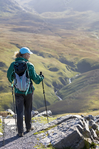 Female hiker on rock trail overlooking grassy river valley below; Letterfrack, County Galway, Ireland photo