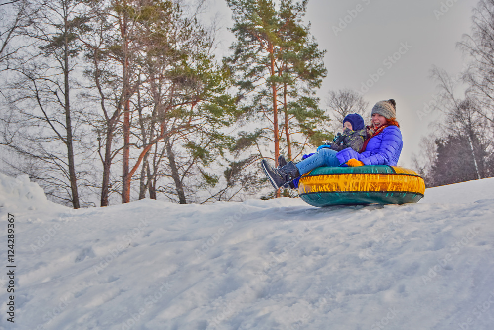 Happy mother and her son on a sleigh ride on winter slope