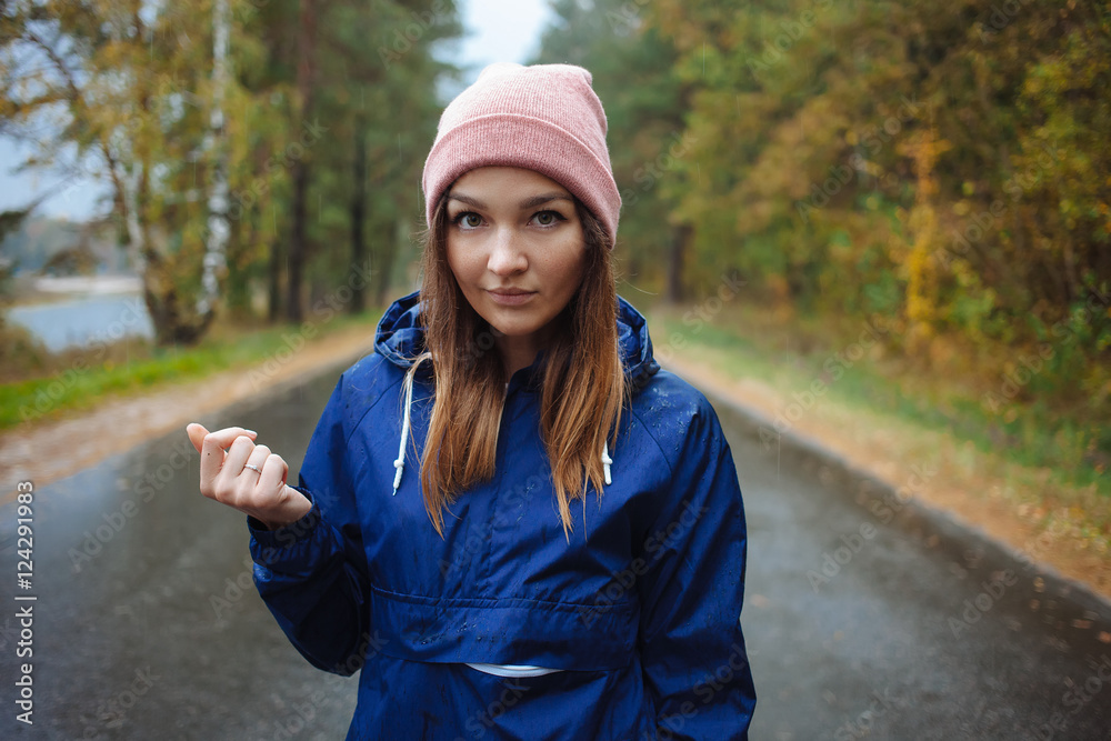 Stylish sporty brunette woman in trendy urban outwear posing in rainy autumn weather on the outdoors road. Vintage filter film saturated color. Fall mood and journey concept. Stylish sporty brunette woman in trendy urban outwear posing in rainy autumn weather on the outdoors road. Vintage filter film saturated color. Fall mood and journey concept.