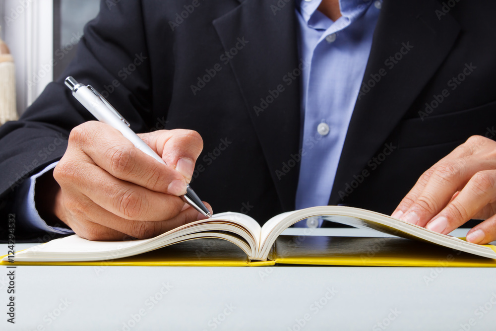 Suited man writing dairy Suited man writing dairy