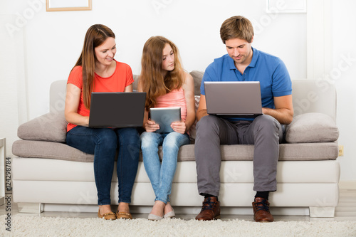 Family Using Laptop And Digital Tablet