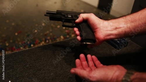 Indoor gun range, man reloads hand gun, close up shot.