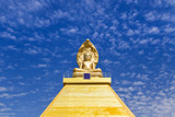 big  golden buddha statue sitting in thai temple with blue sky background