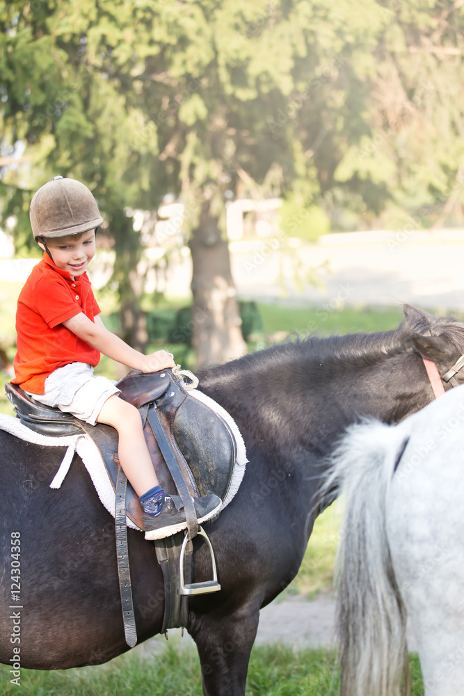 a boy wearing orange shirt and a helmet sitting on top of a horse a boy wearing orange shirt and a helmet sitting on top of a horse
