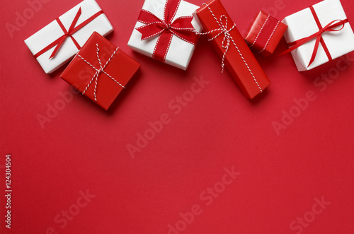 Christmas gifts presents on red background. Simple, classic red and white wrapped gift boxes with ribbon bows horizontal top border. photo
