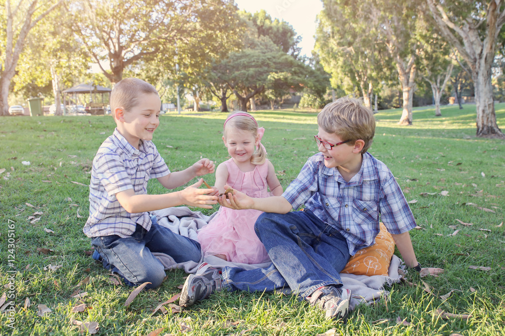 Fototapeta premium Happy brothers and sister playing at the park