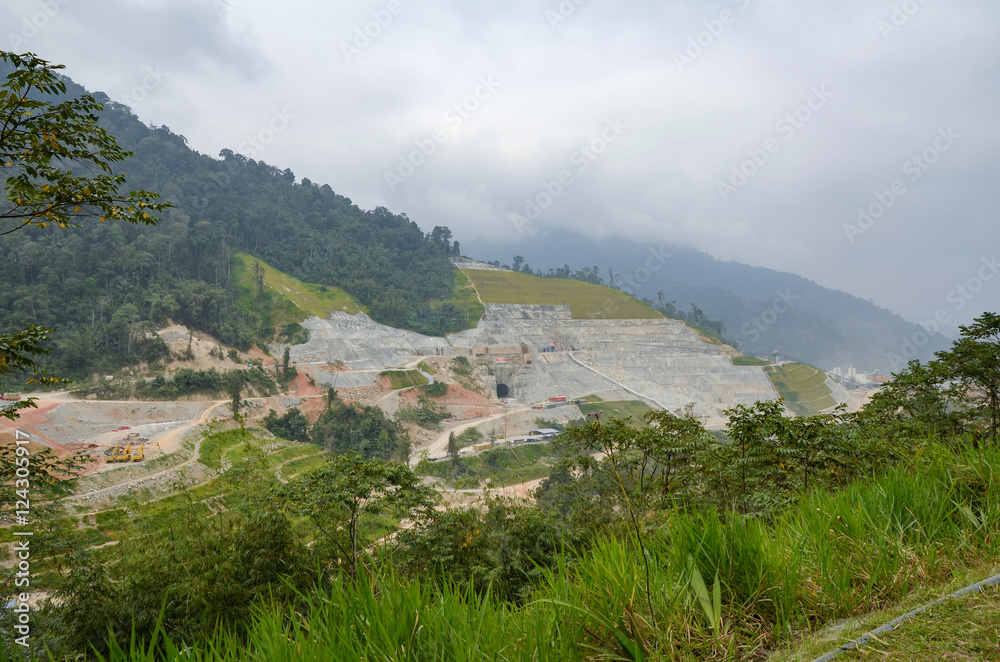 Hydroelectric dam under construction, surrounded by cloudy sky a