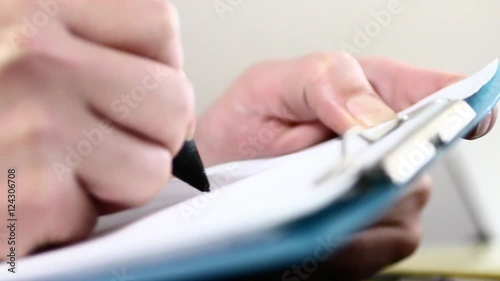 バインダーの書類にペンで書く男性の手元クローズアップ：マクロレンズ使用ピント浅め