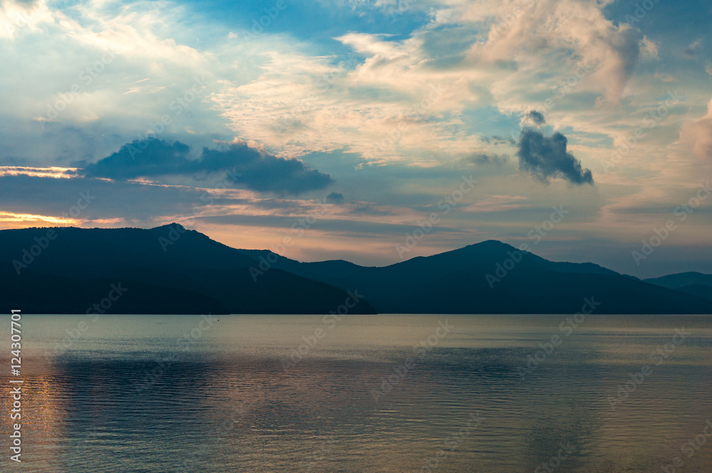 Caldera lake on dusk with mountain silhouettes on the background