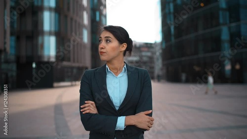 4k. Ultra HD. Portrait of young confident sexy caucasian businesswoman with arms crossed disapproval Your opinion. Pomade, brownhair, lady. Negation concept. Formal suit. Modern glass buildings bg