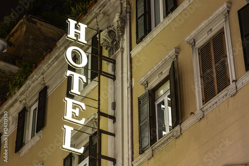 Hotel glowing sign on old facade at night. Europe