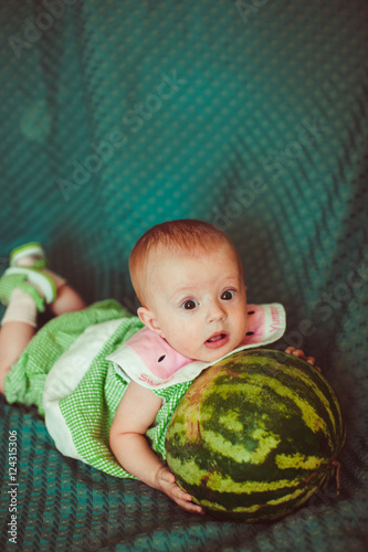 little newborn baby holding a big pumpkin