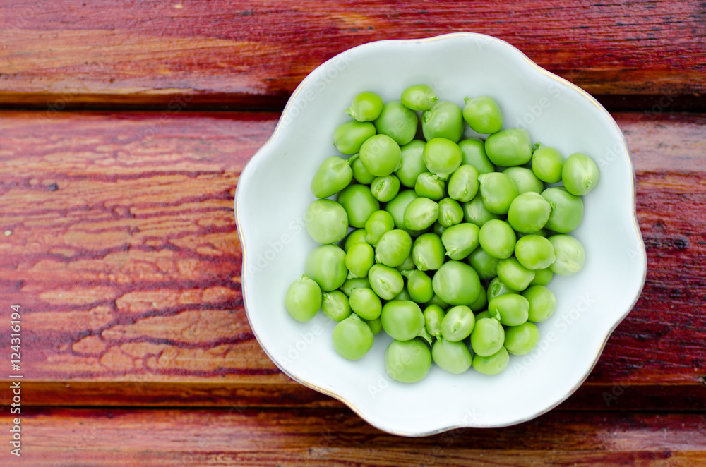 Fresh green peas on white plate, close-up