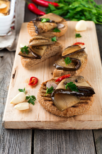 Bruschetta with marinated eggplant with chilli, garlic and parsley on a wooden stand. Selective focus.