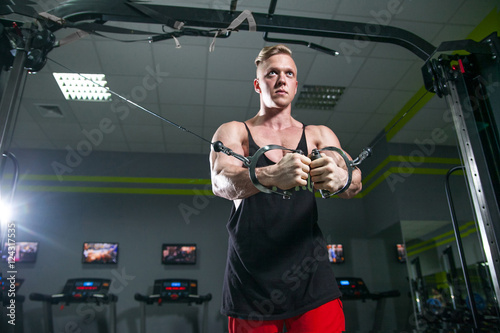 Photography A strong man with muscles training on simulators in gym