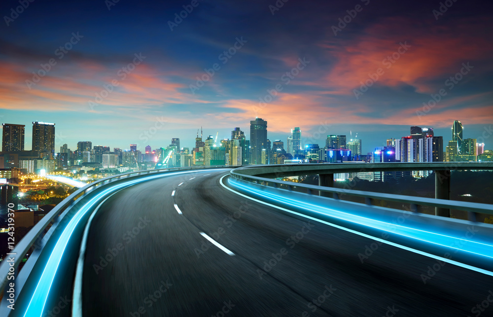 Obraz premium Blue neon light highway overpass motion blur with city skyline background , night scene .
