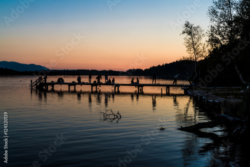 Kirchsee in Oberbayern mit Badesteg, Badegästen und Alpenblick nach Sonnenuntergang © Andy Ilmberger