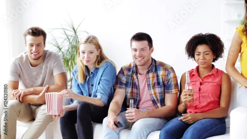 friends with popcorn and beer watching tv at home photo