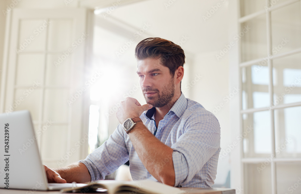 Young man at home working on laptop Young man at home working on laptop