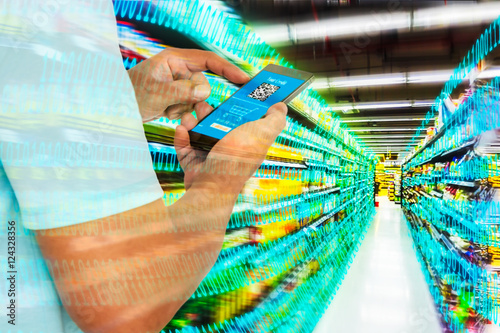 Digital revolution in retail market concept. Double exposure of business man using smart phone with shoping application on screen and abstract digital binary code with supermarket aisle,motion blur.