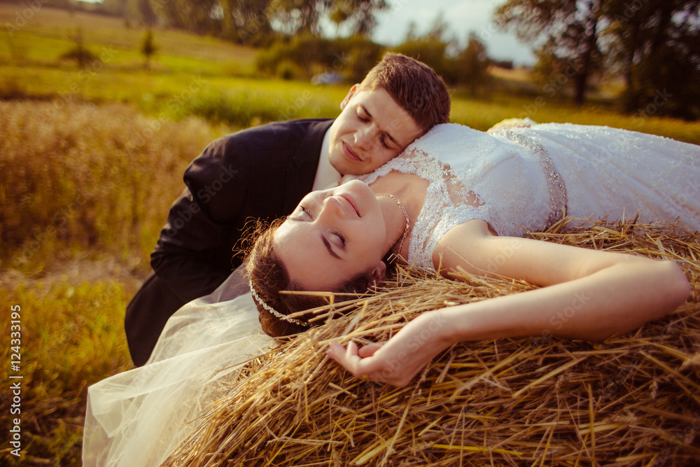 Handsome groom leans to a bride dreaming on the hay Handsome groom leans to a bride dreaming on the hay