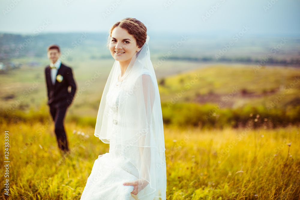 Attractive bride smiles light while standing on the filed before Attractive bride smiles light while standing on the filed before